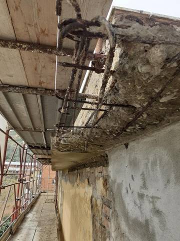 Balcone in cemento armato con ferri d'armatura scoperti durante il ripristino