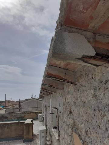Cornicione in cemento armato degradato con ferri d'armatura esposti prima del ripristino