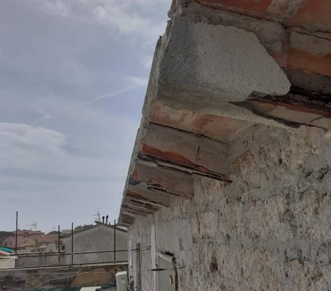 Cornicione in cemento armato degradato con ferri d'armatura esposti prima del ripristino
