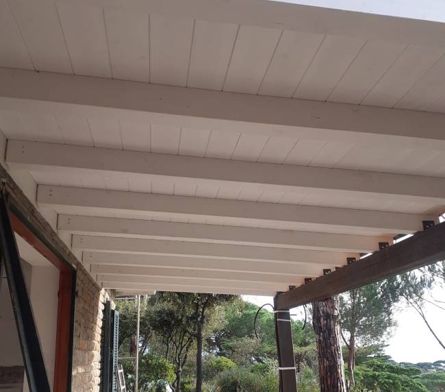 Portico con travi in legno e lavori di pavimentazione esterna in una villa