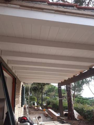 Portico con travi in legno e lavori di pavimentazione esterna in una villa